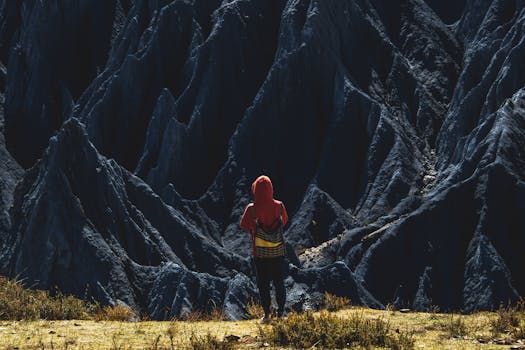 A lone hiker stands before stunning dark rock formations in Sichuan, China.