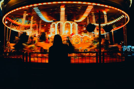 A silhouette captures a spinning carousel in nighttime London with vibrant light trails.