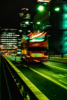 Blurred motion of a double-decker bus in London's glowing cityscape at night.