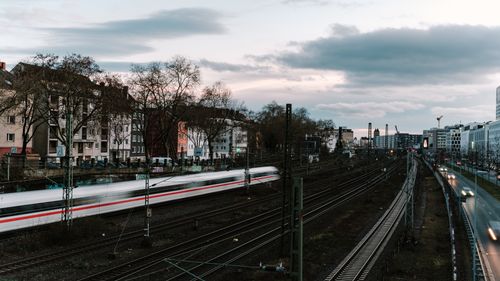 Free A high-speed train travels through a bustling urban area under a cloudy evening sky. Stock Photo