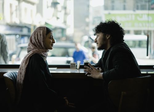 Free A candid moment of two adults engaging in conversation at a café. Stock Photo