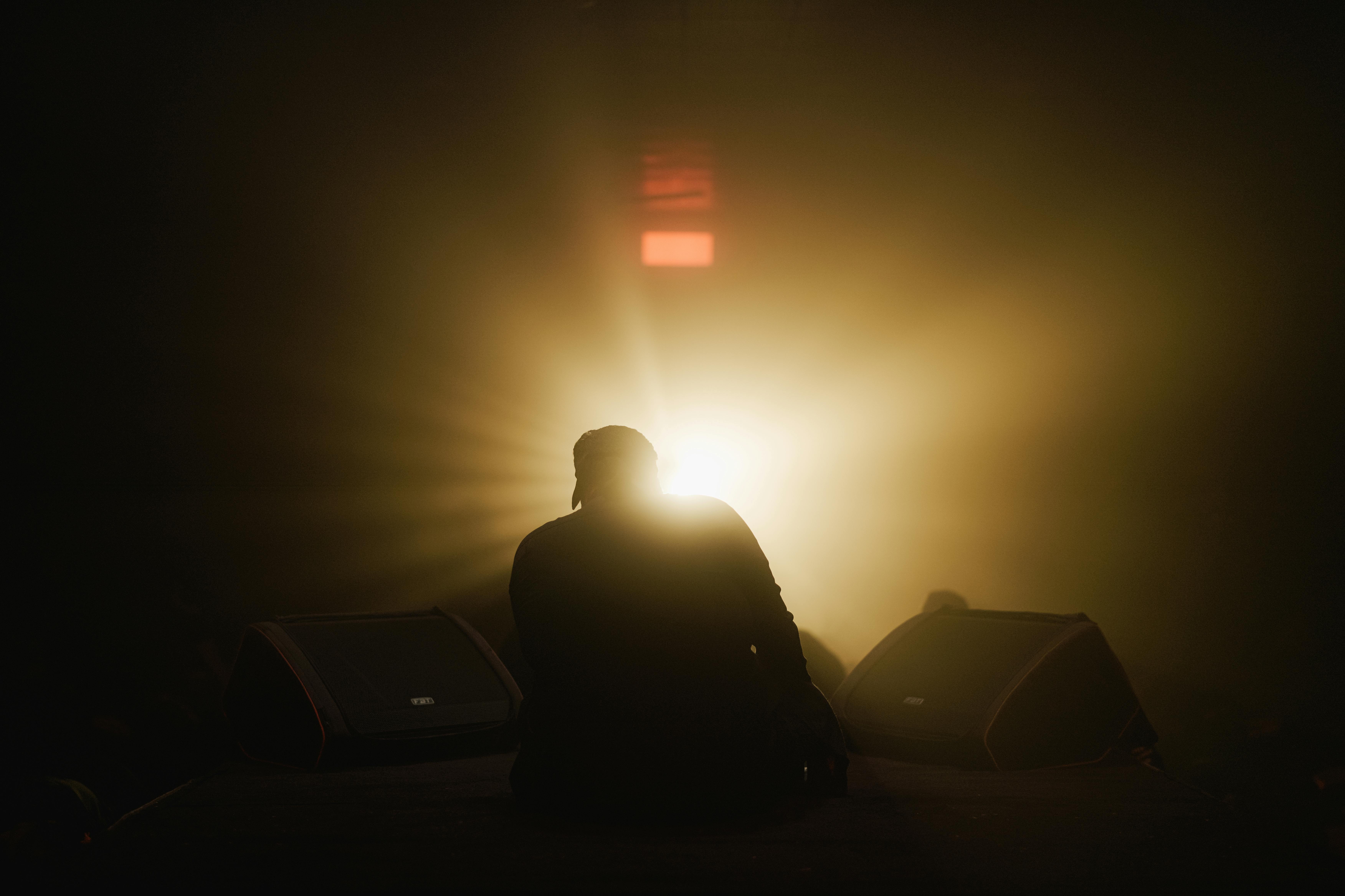 Ücretsiz Sahnede bir sanatçının silüeti, dramatik arka ışıklandırmayla, gizem ve merak duygusu uyandırıyor. Stok Fotoğraflar