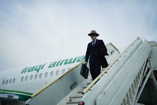 A businessman in formal attire exits an Iraqi Airways plane on a mobile stairway.