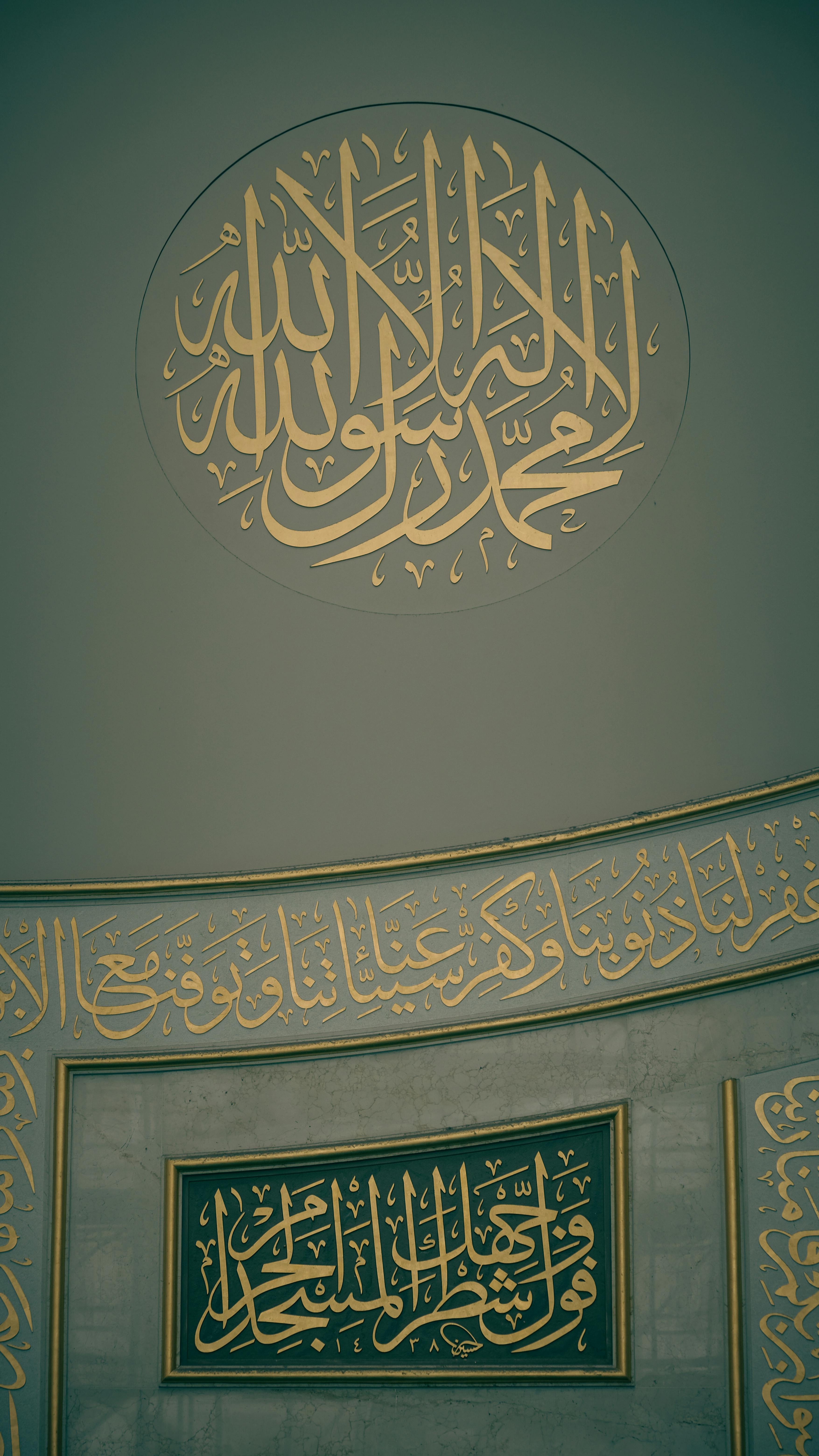 Intricate gold Islamic calligraphy on mosque wall interior, showcasing religious art.