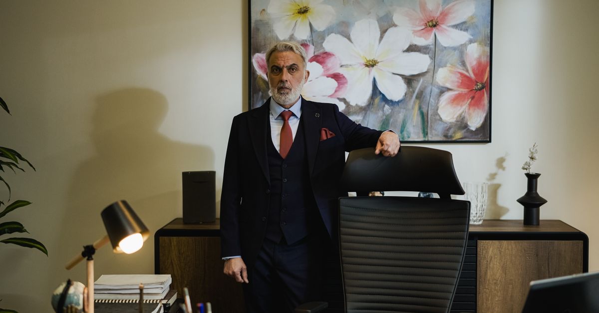 Distinguished mature businessman in a suit standing confidently in a modern office.