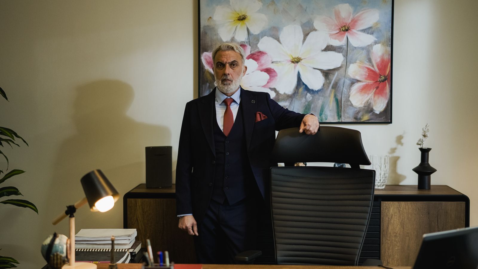 Distinguished mature businessman in a suit standing confidently in a modern office.