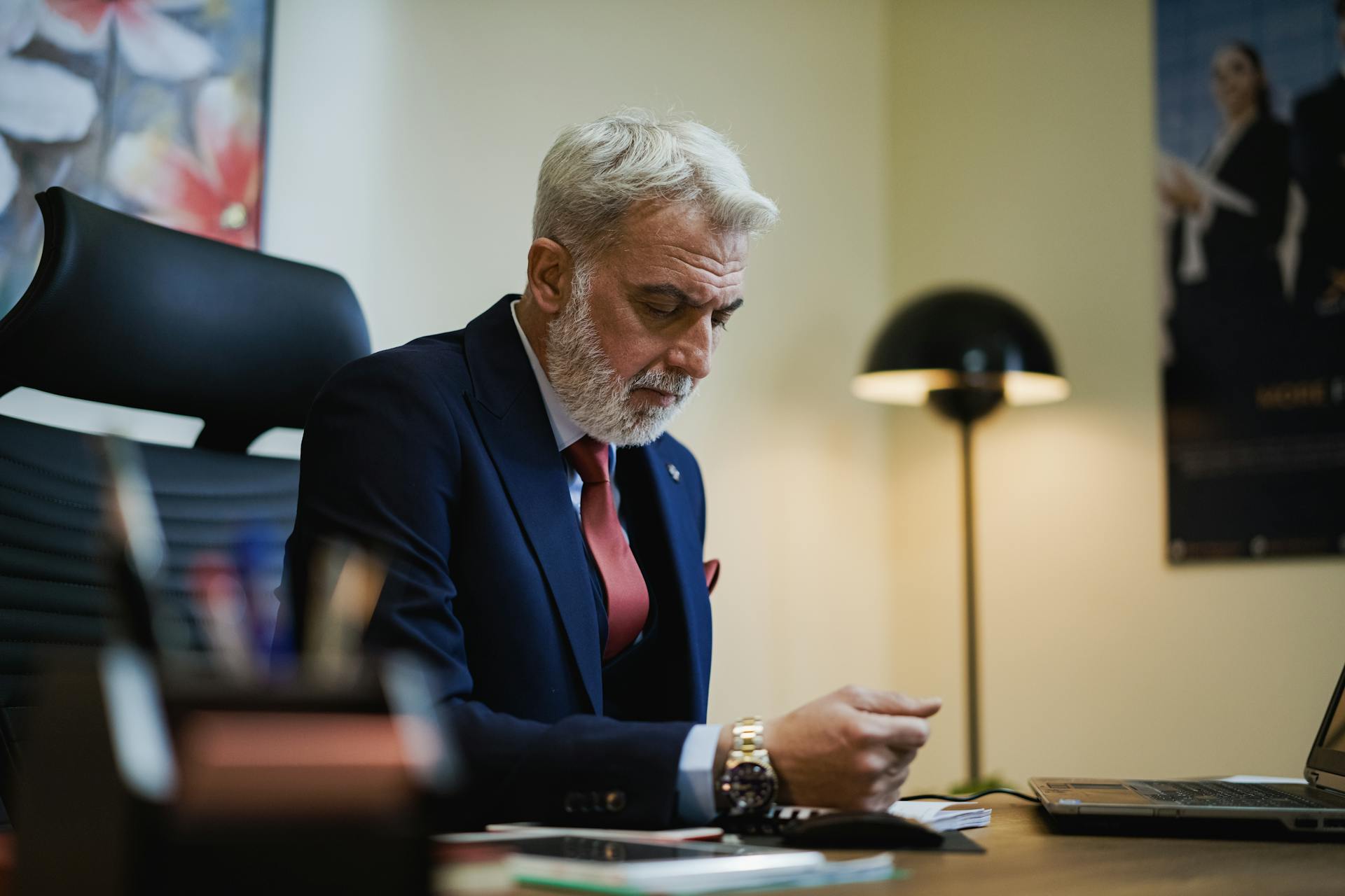 Senior businessman in formal attire working at his office desk with focused expression.