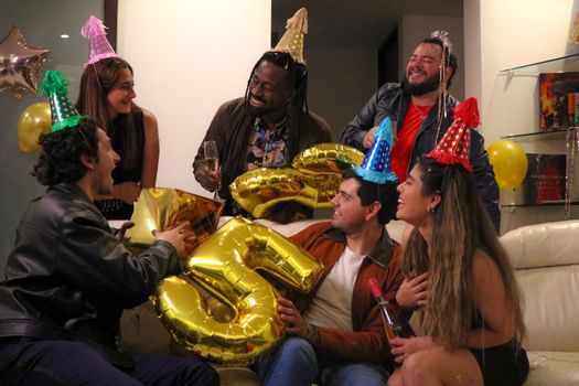 Group of adults celebrating 35th birthday with hats and balloons indoors.