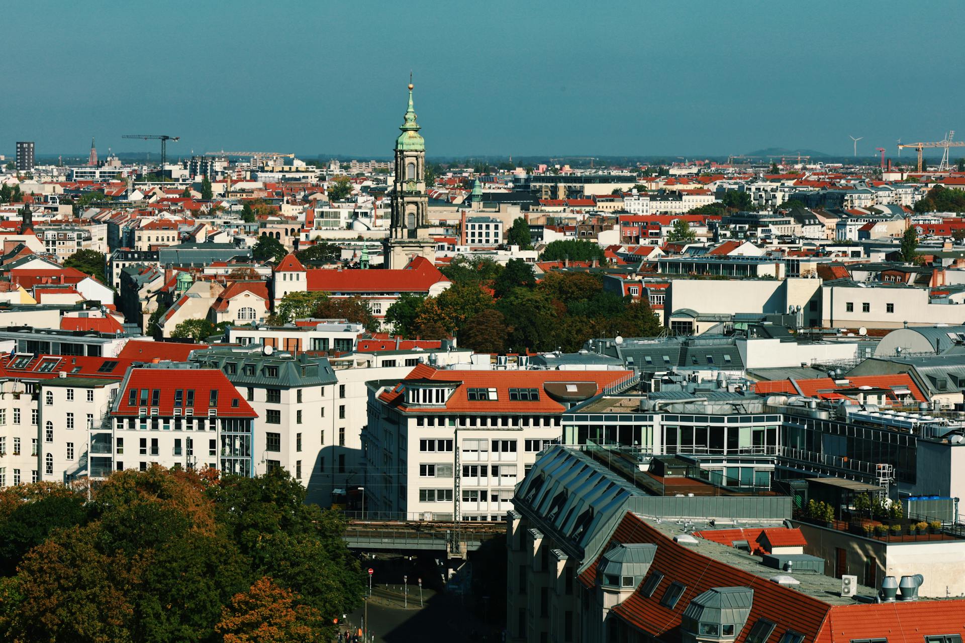 A vibrant aerial cityscape of Berlin showcasing architecture and the iconic spire against a clear sky.