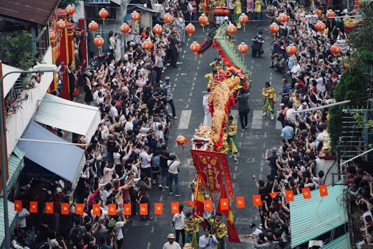 Aerial view of a colorful dragon dance procession during a lively street festival with crowds.