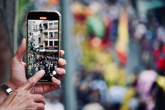 A vibrant street parade captured on a mobile phone, showcasing urban life.
