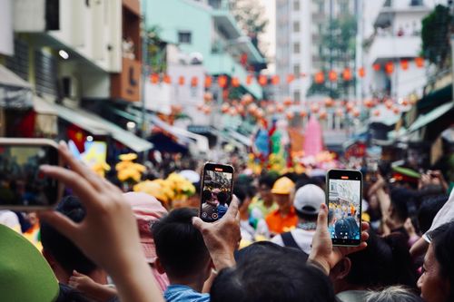Free Vibrant street festival scene filled with people capturing the moment on their smartphones. Stock Photo