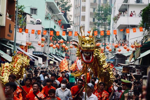 Colorful dragon dance in a bustling street parade with traditional decorations.