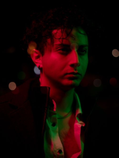 Free Artistic portrait of a man in mixed red and green light, creating a moody atmosphere. Stock Photo