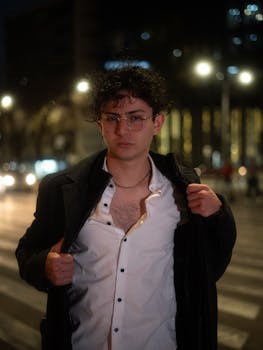 Stylish young man poses confidently on a bustling nighttime street in Mexico City.