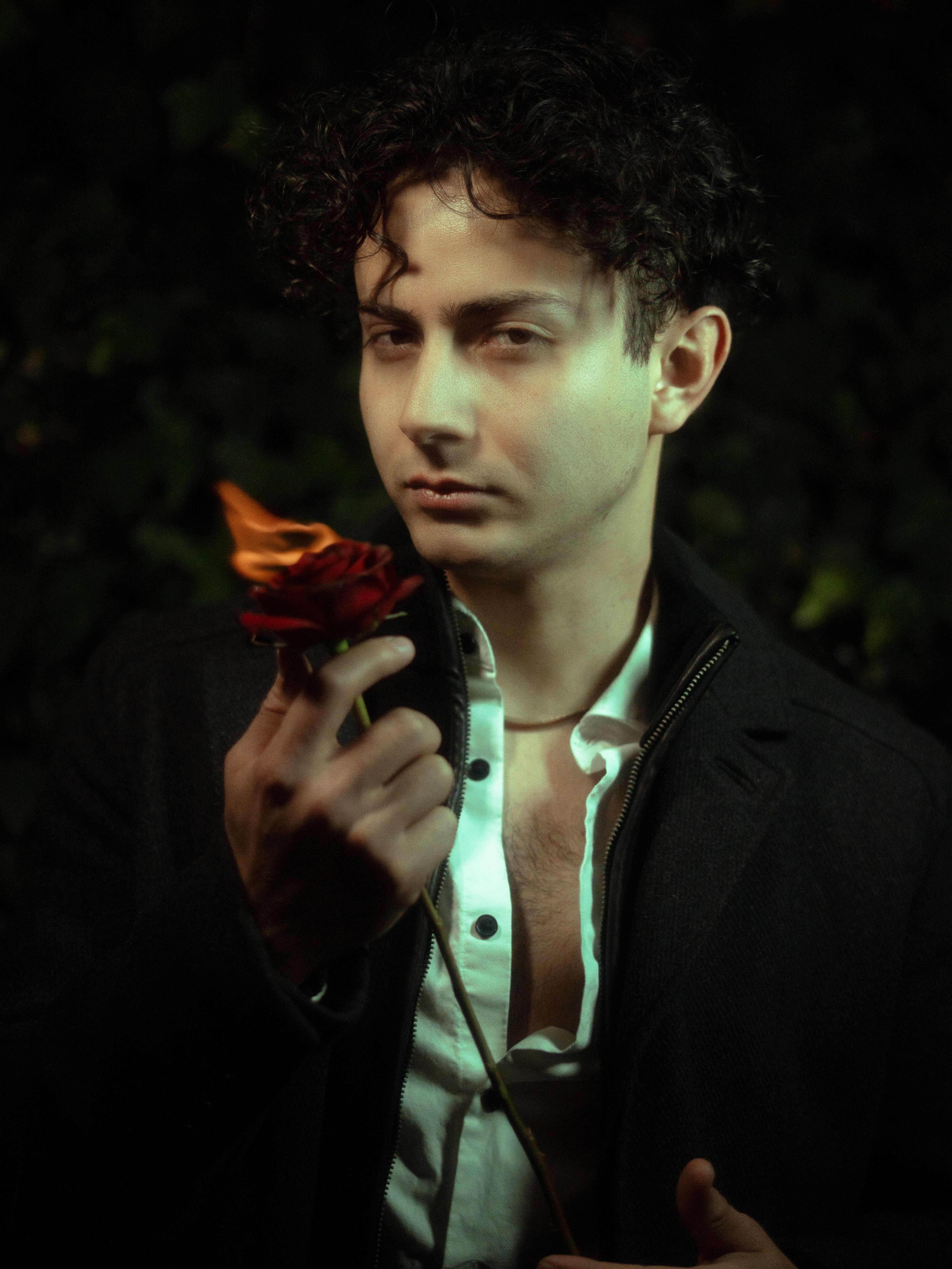 Dramatic portrait of a man holding a rose with a flame, showcasing romanticism.
