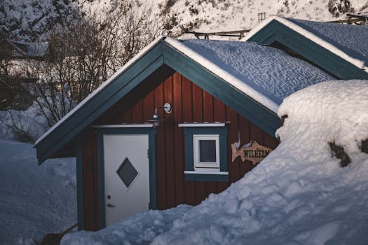 A charming red cabin nestled in a snowy landscape, showcasing winter tranquility.