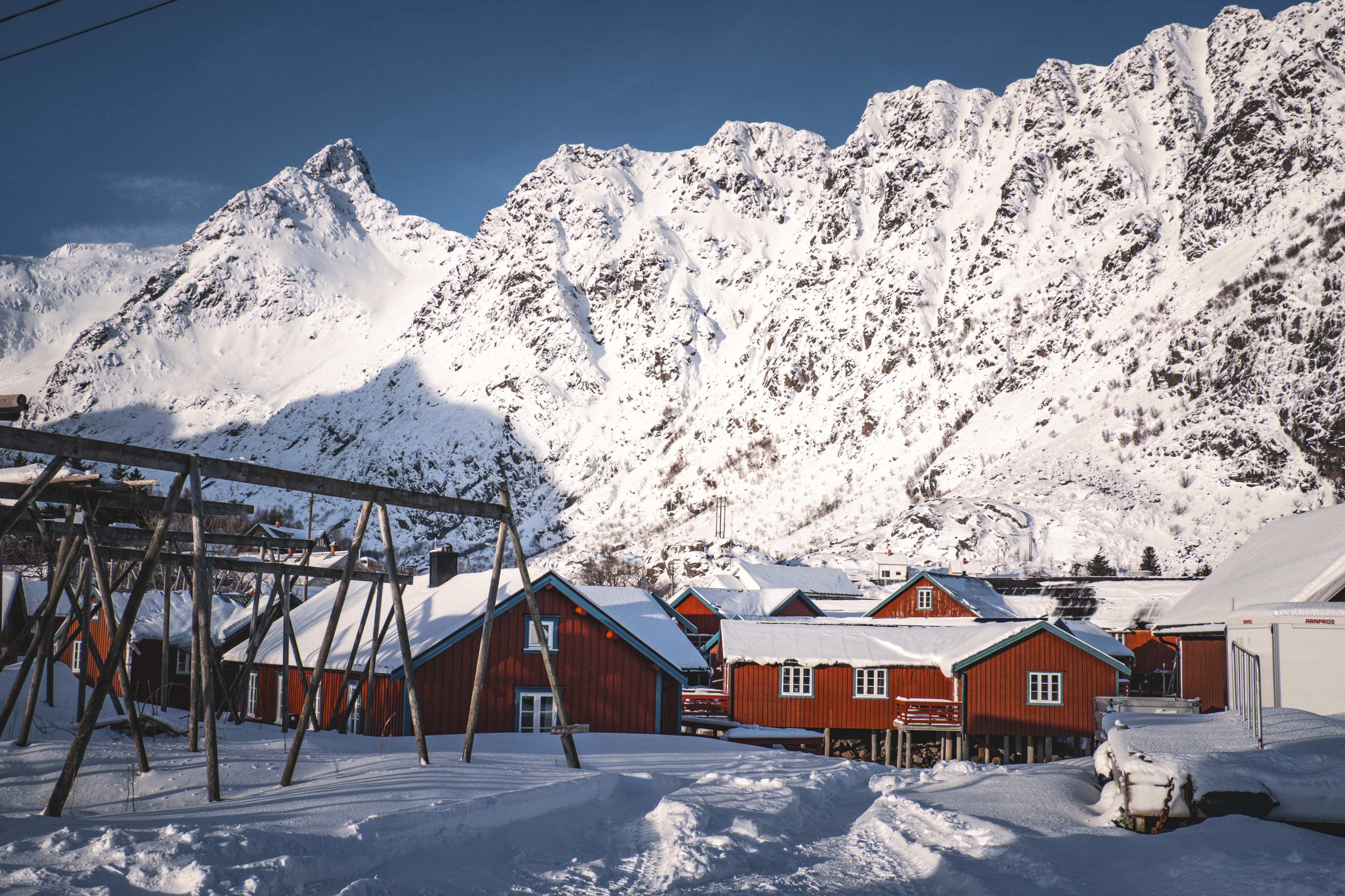 Tradisjonelle røde trehus i snødekt norsk bygd med fjell i bakgrunnen