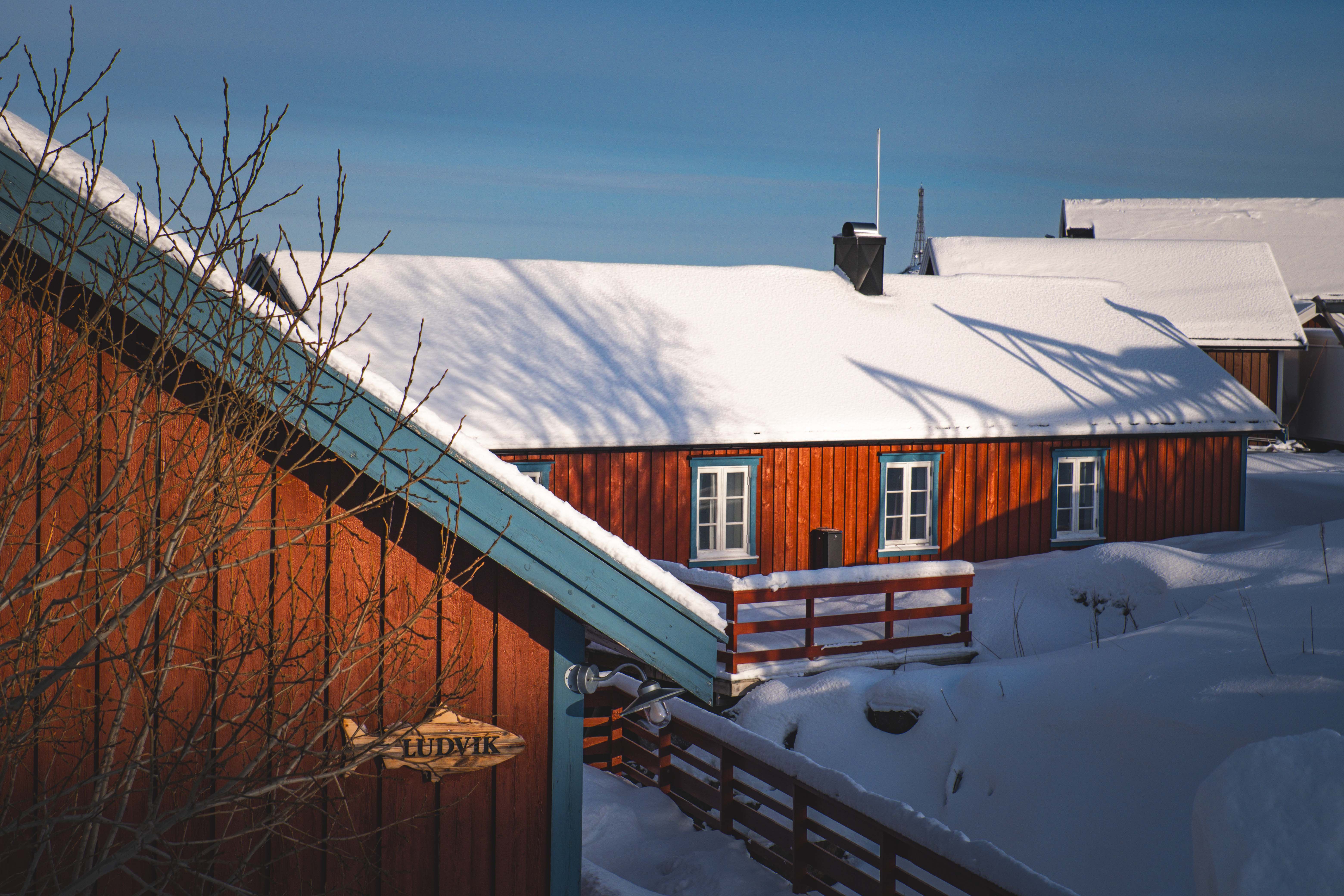 Snowy Scandinavian cabin in winter sunlight · Free Stock Photo