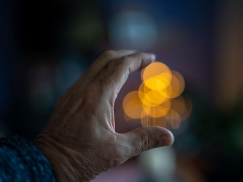 Free Intimate close-up of a hand framing beautiful bokeh circles in warm orange tones. Stock Photo
