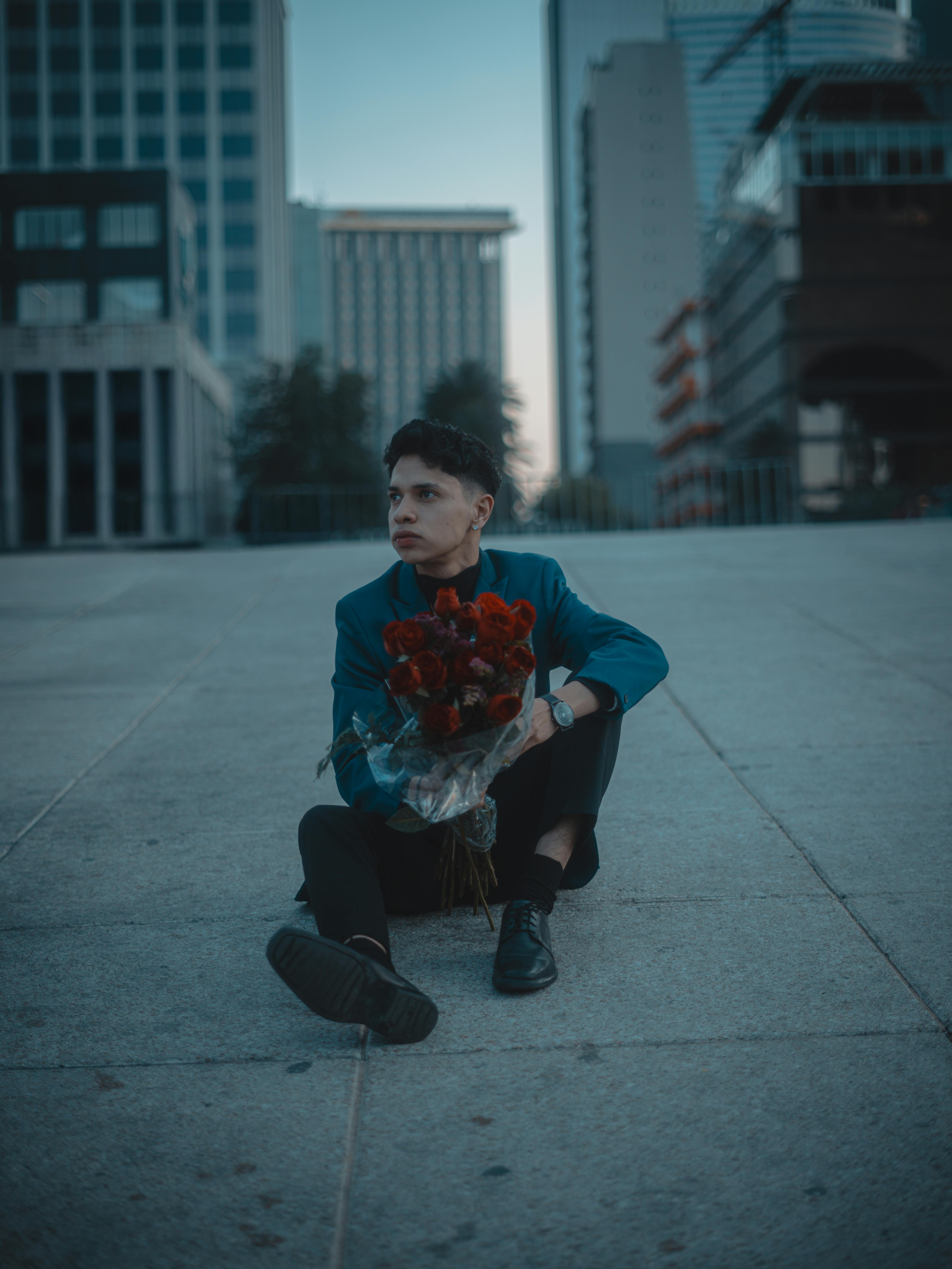 A thoughtful person holding roses in an urban setting, evoking romance.
