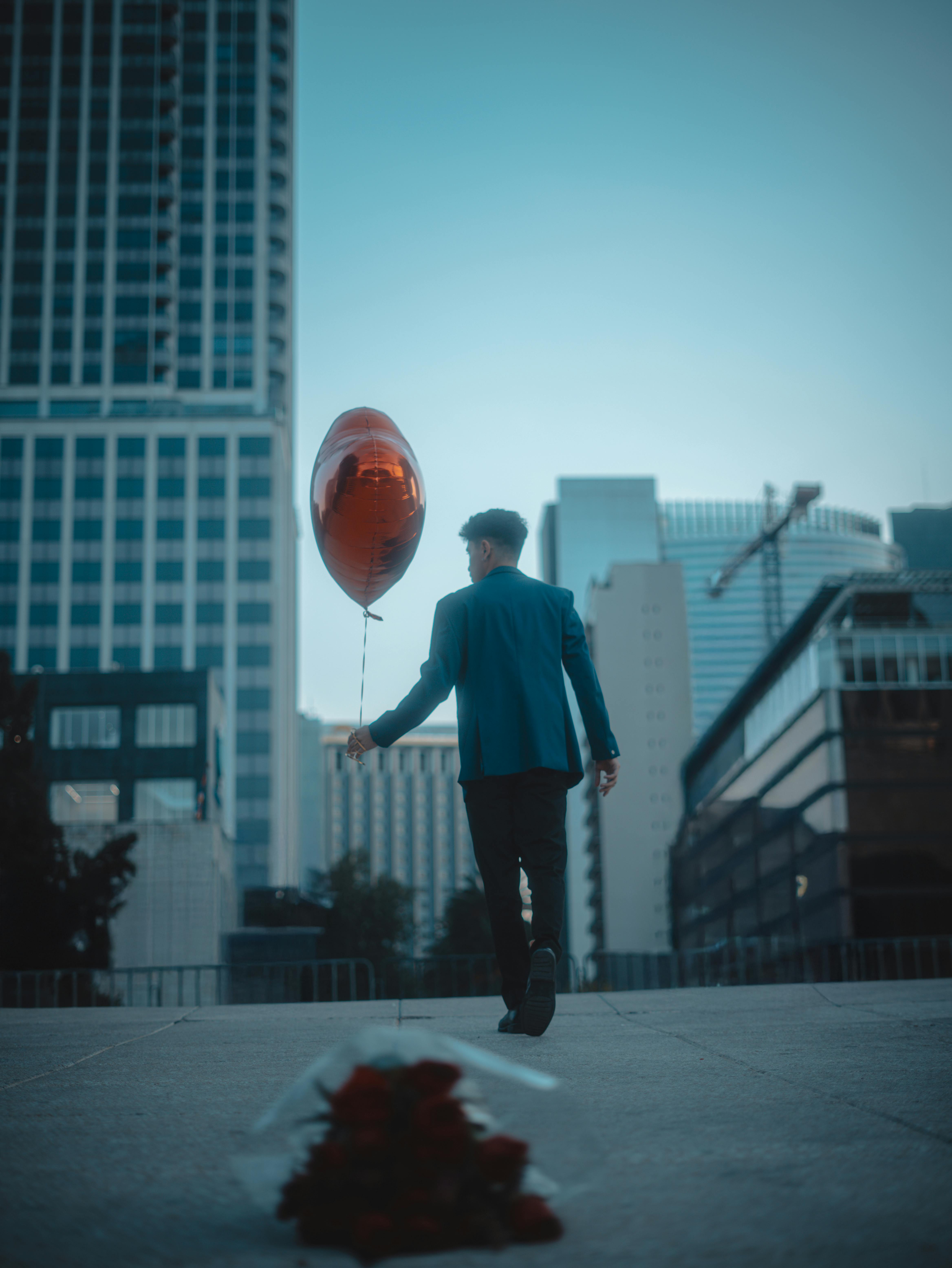 A man walks through Mexico City with a heart-shaped balloon, conveying romance and urban style.