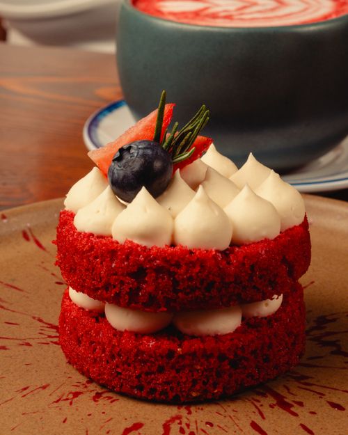 Free Delicious red velvet cake with creamy frosting, garnished with blueberry and rosemary. Stock Photo