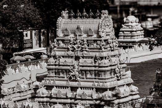 A detailed black and white image of an ornate Hindu temple tower with intricate carvings.