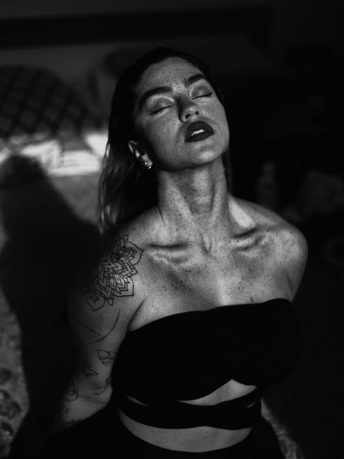 Artistic black and white portrait of a tattooed woman with closed eyes.