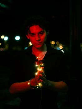 A young man illuminated by red and green lights, creating a romantic, cinematic mood.
