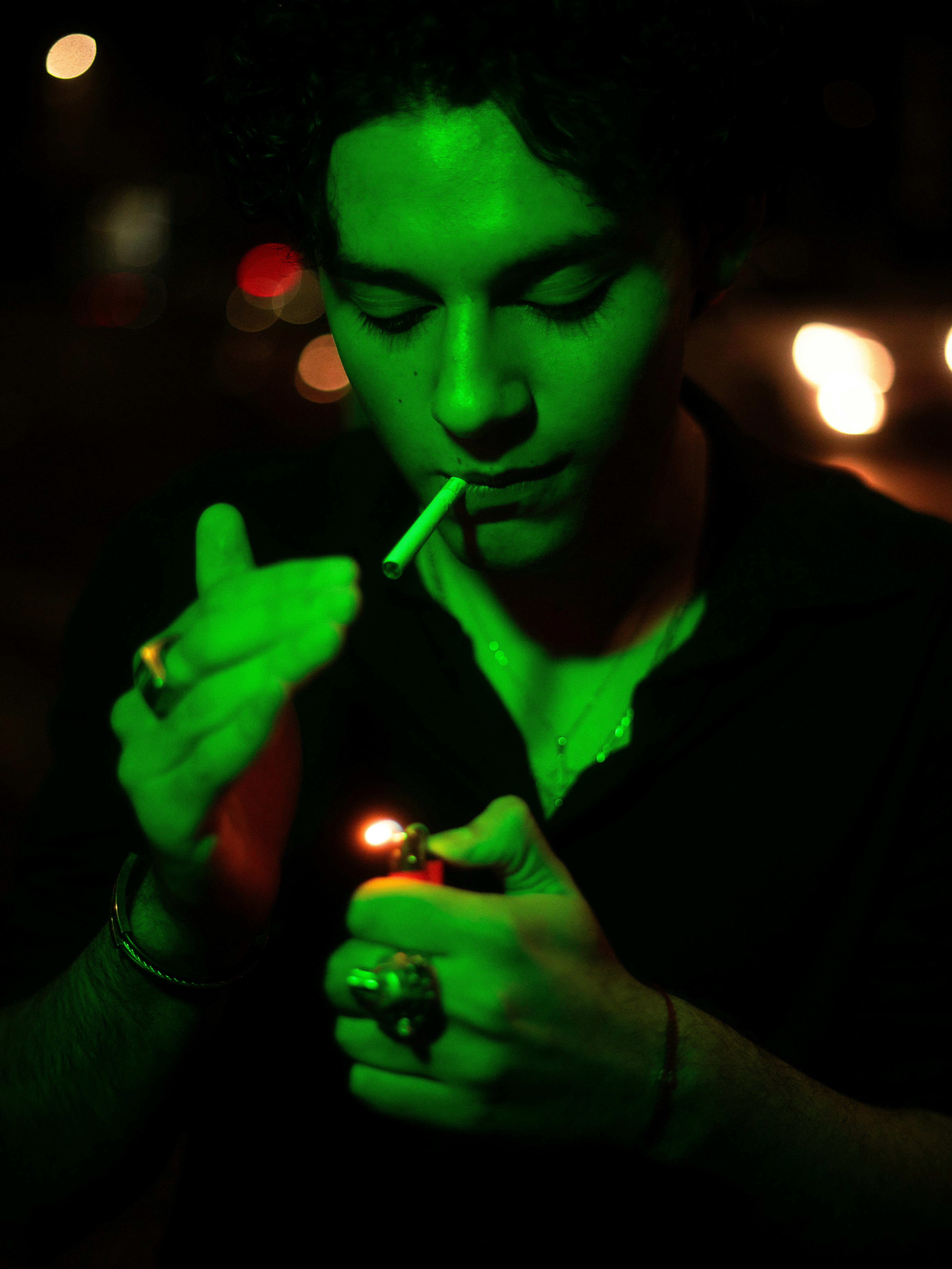 moody portrait of man lighting cigarette at night