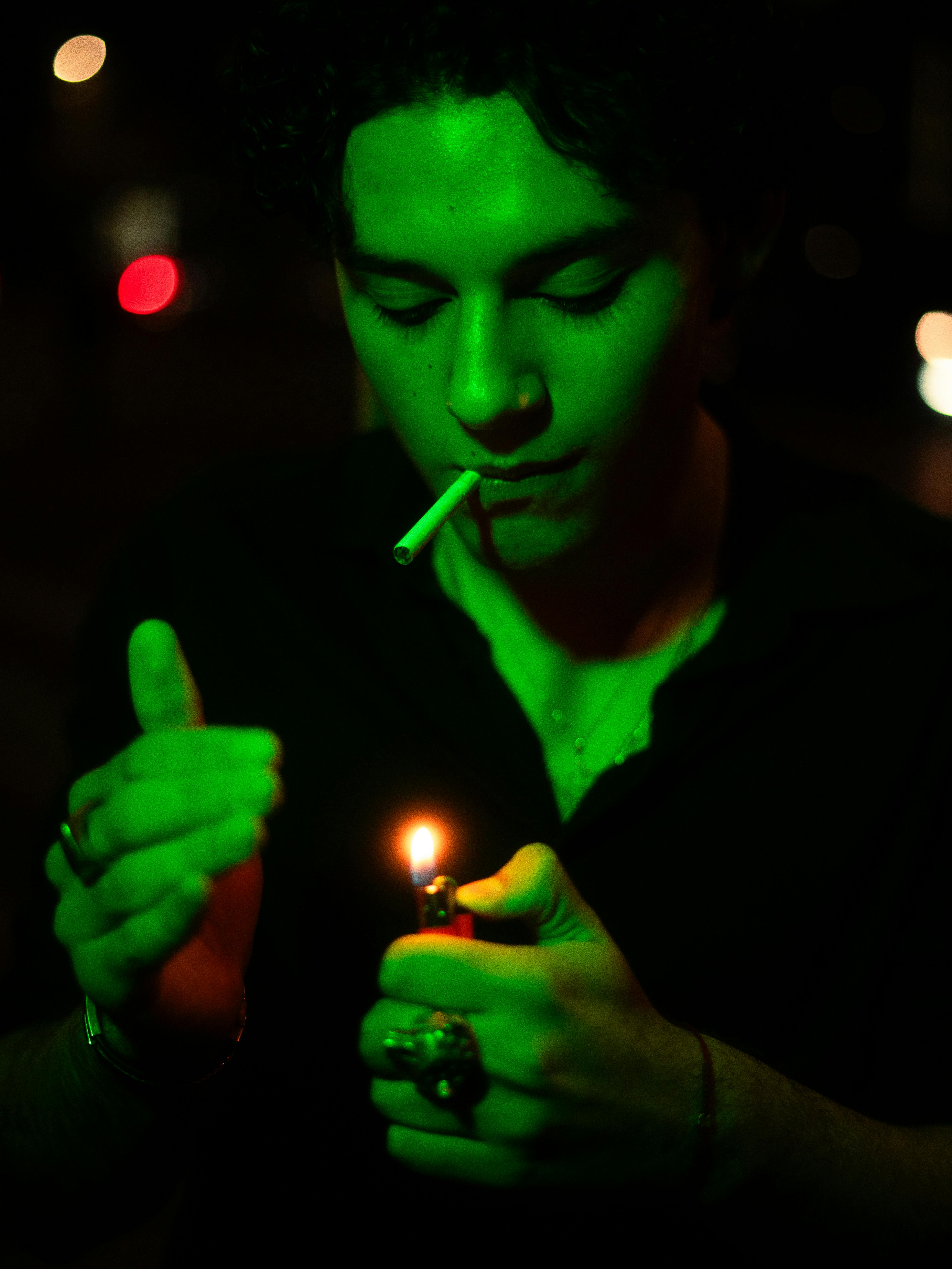 moody portrait of man lighting cigarette at night