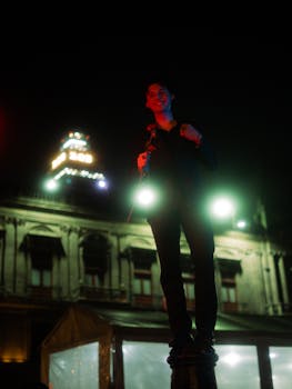 Portrait of a young man standing in front of illuminated building at night in Mexico City.