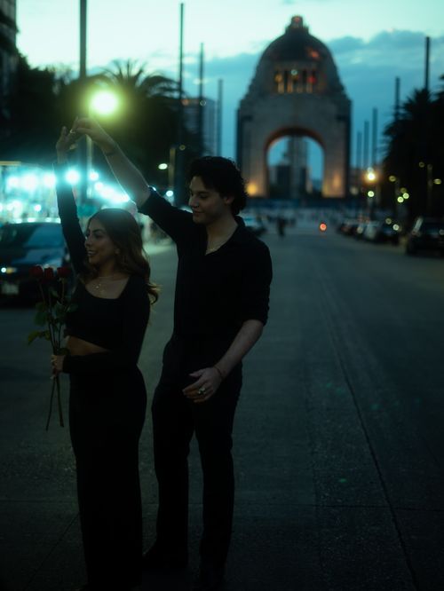 Free A couple shares a romantic moment with roses by a historic monument in Mexico City at night. Stock Photo