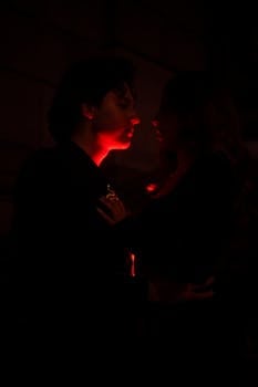 A romantic moment captured between a couple illuminated by red light in Mexico City.