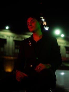 A stylish portrait of an elegant individual at night with city lights creating a moody atmosphere.