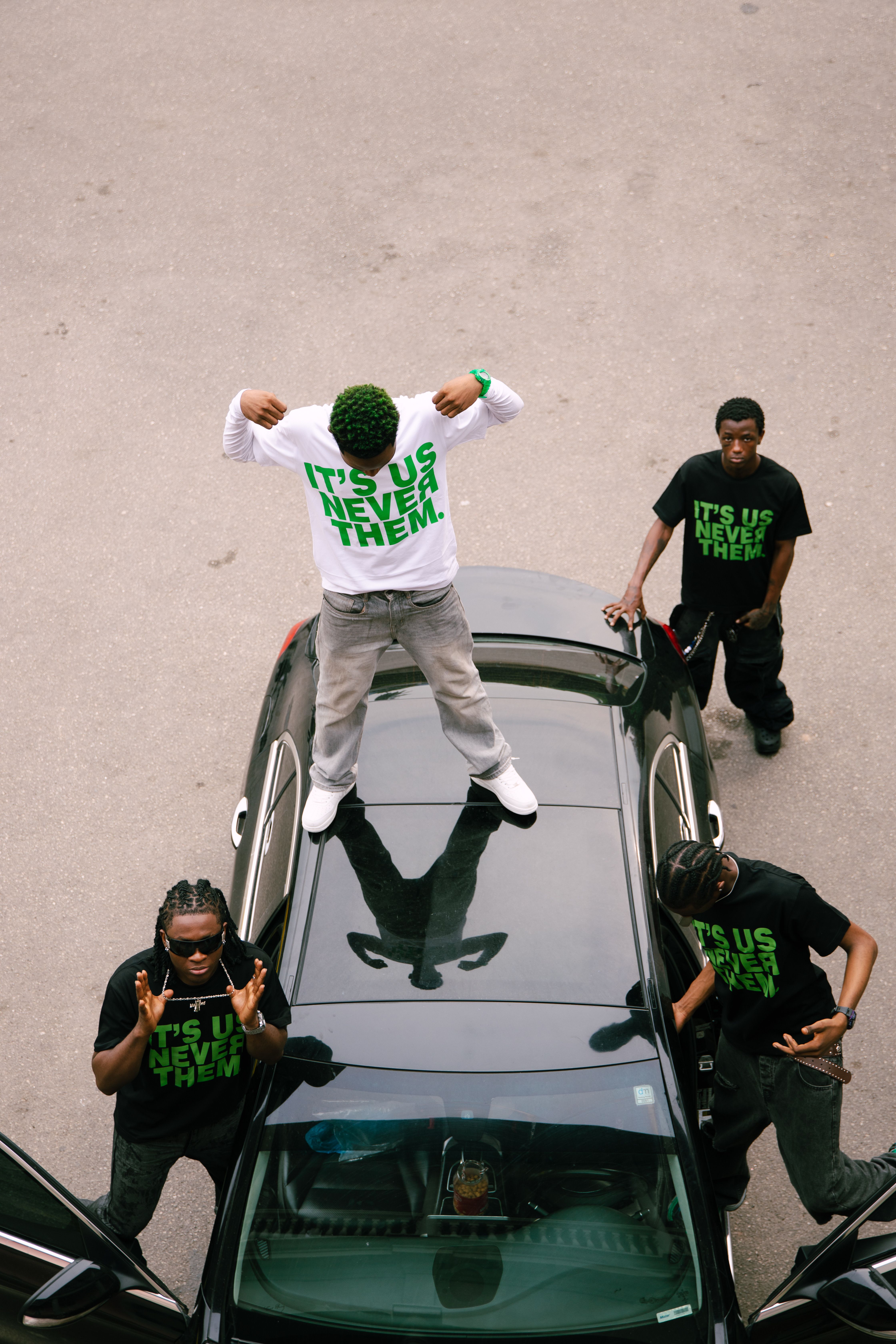 Group of young men posing on a car, wearing statement t-shirts with urban style.
