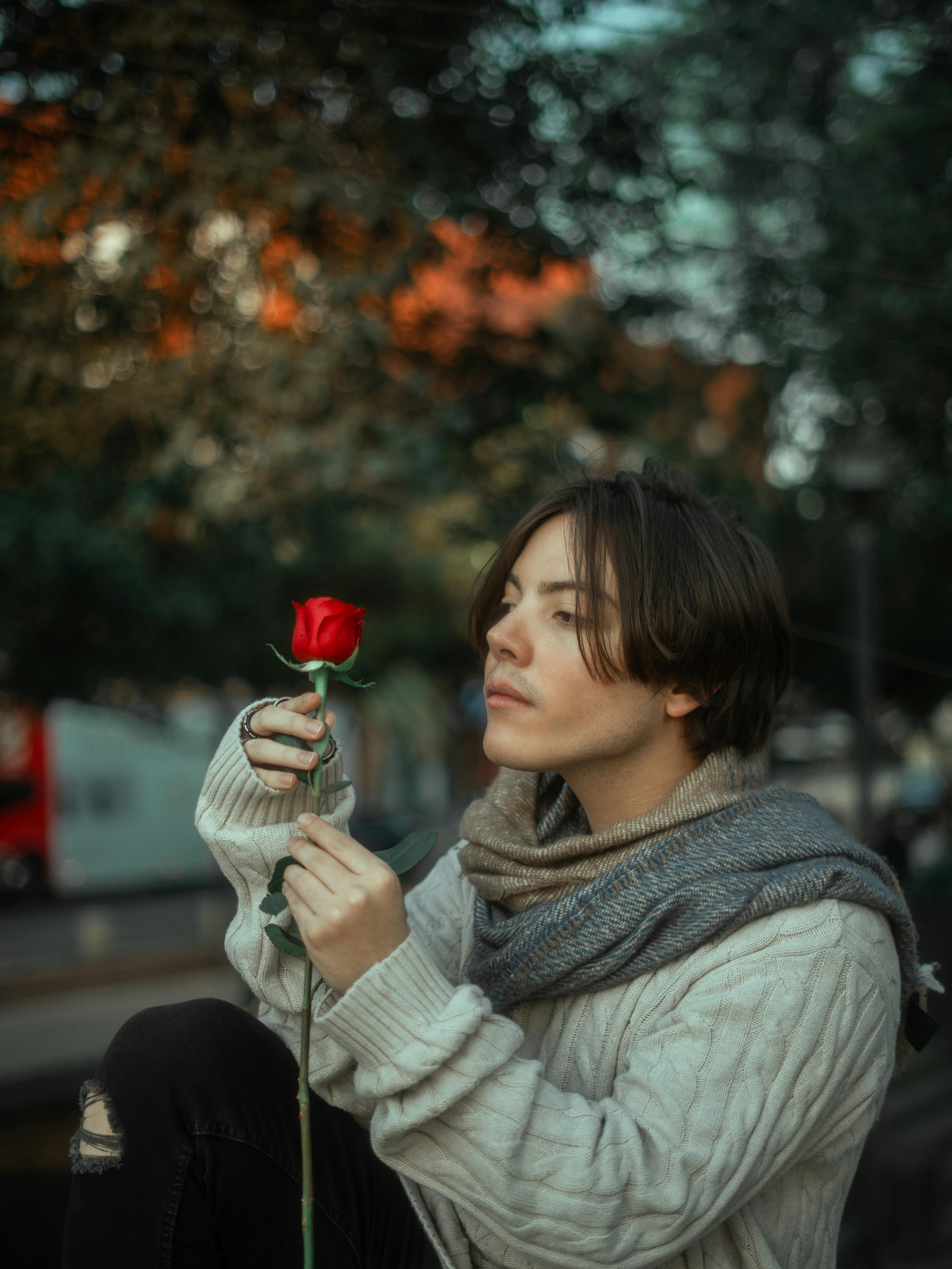 Free A contemplative man holding a red rose in a serene outdoor setting in Mexico City. Stock Photo