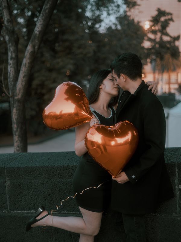A Couple Holding a Heart Shaped Balloon Standing on a Sidewalk · Free ...