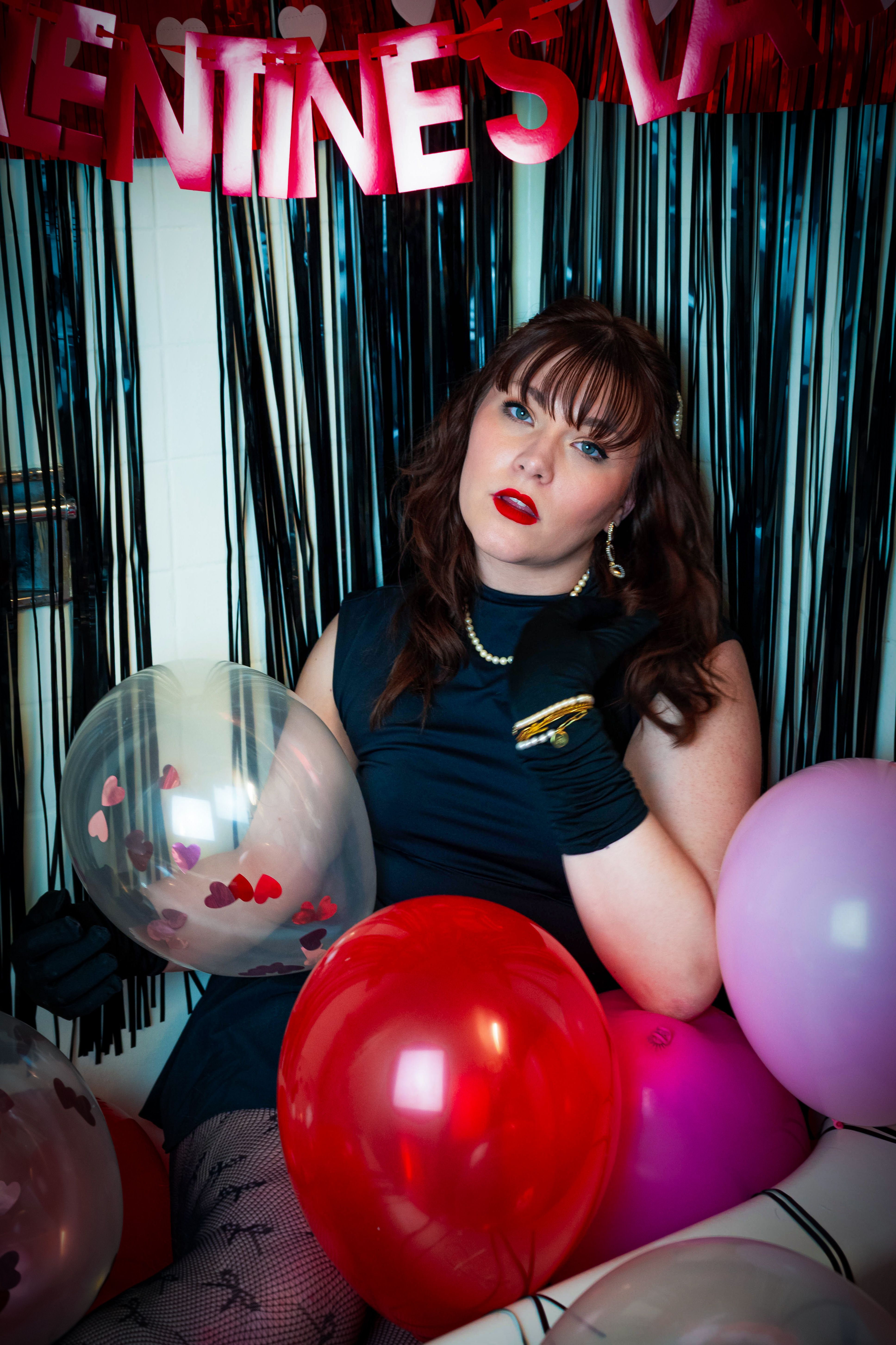 Stylish woman in vintage setting with balloons, celebrating Valentine's Day ambiance.