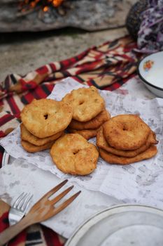 Golden fried bread stacked on paper napkins during an outdoor picnic.
