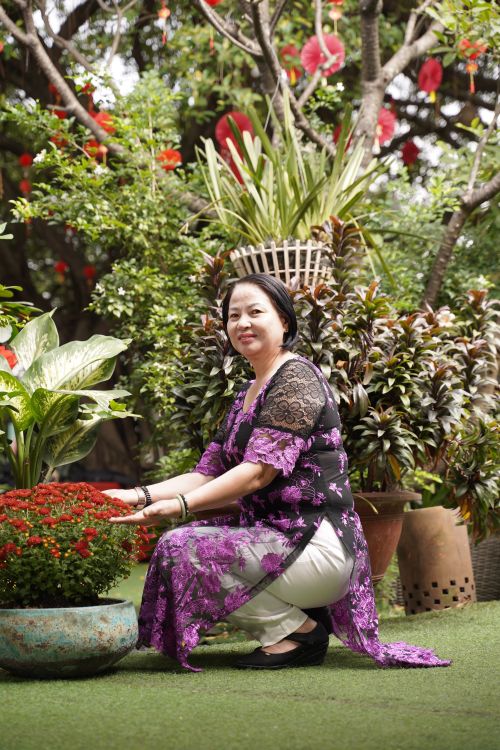 Free Woman in traditional dress enjoying a lush garden setting, surrounded by vibrant plants. Stock Photo