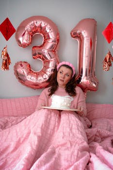 Adult woman in pink celebrating 31st birthday with cake and balloons indoors.