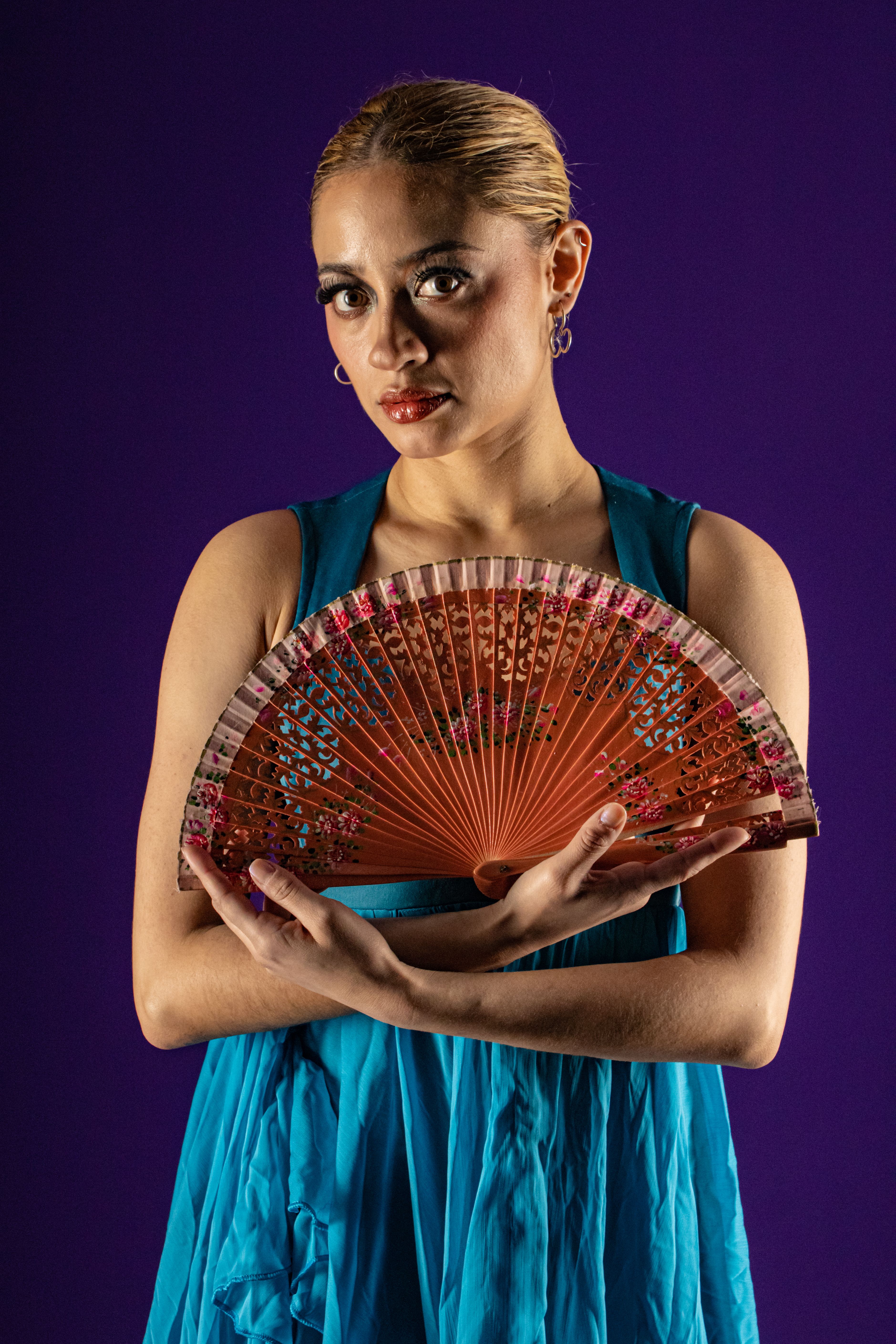 Elegant portrait of a flamenco dancer in a vibrant blue dress holding a red fan.