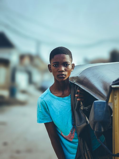 Free Teenager standing beside a rickshaw, capturing urban life dynamics. Stock Photo
