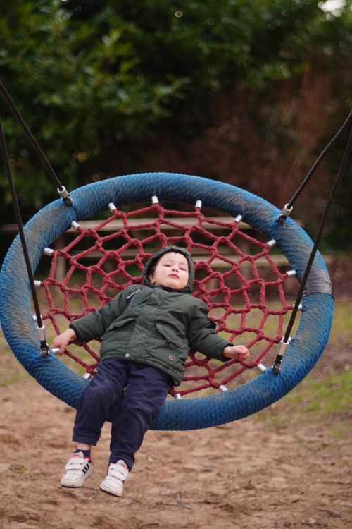 Child enjoying playtime on a rope swing outdoors