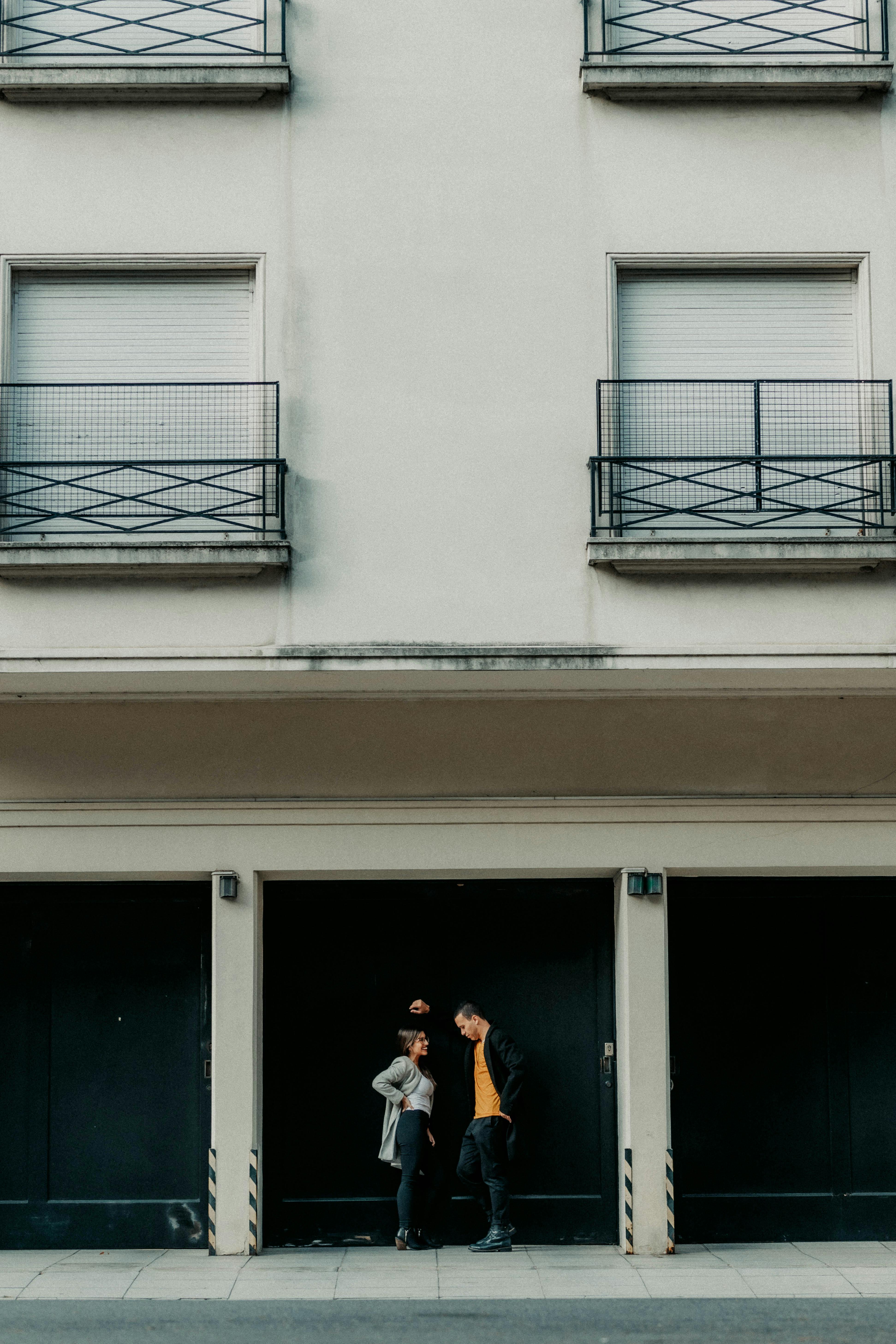 Two adults engage in conversation in front of an urban building facade in Buenos Aires.