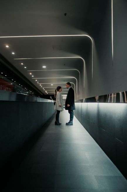A couple stands in a modern hallway, creating a serene and intimate atmosphere.