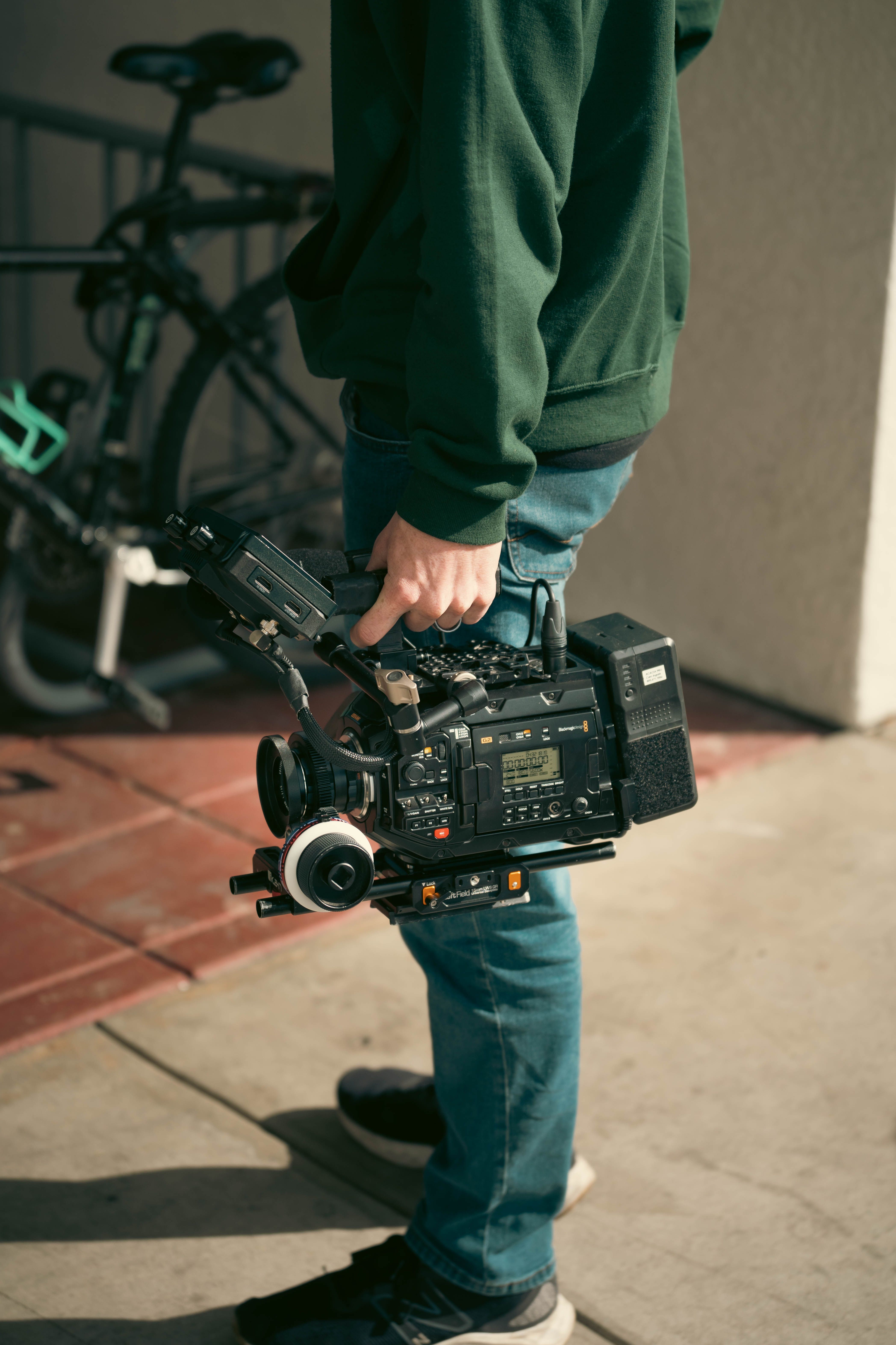 Videographer Holding Professional Camera Outdoors · Free Stock Photo