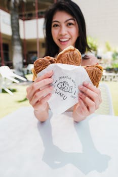 A cheerful woman holding delicious taiyaki outdoors on a sunny day.